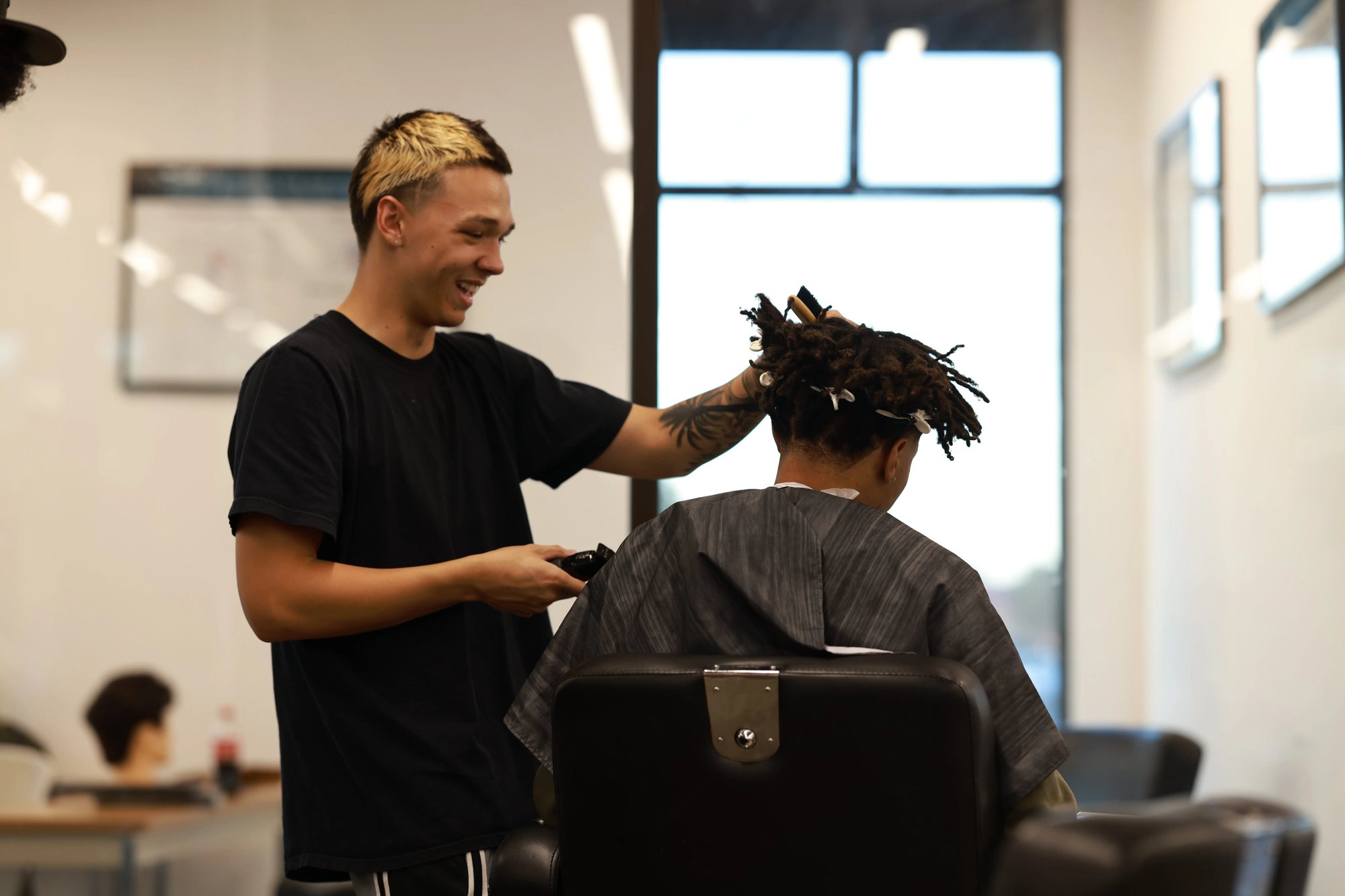 Jeremiah smiling while working on a client's locs in the barber chair
