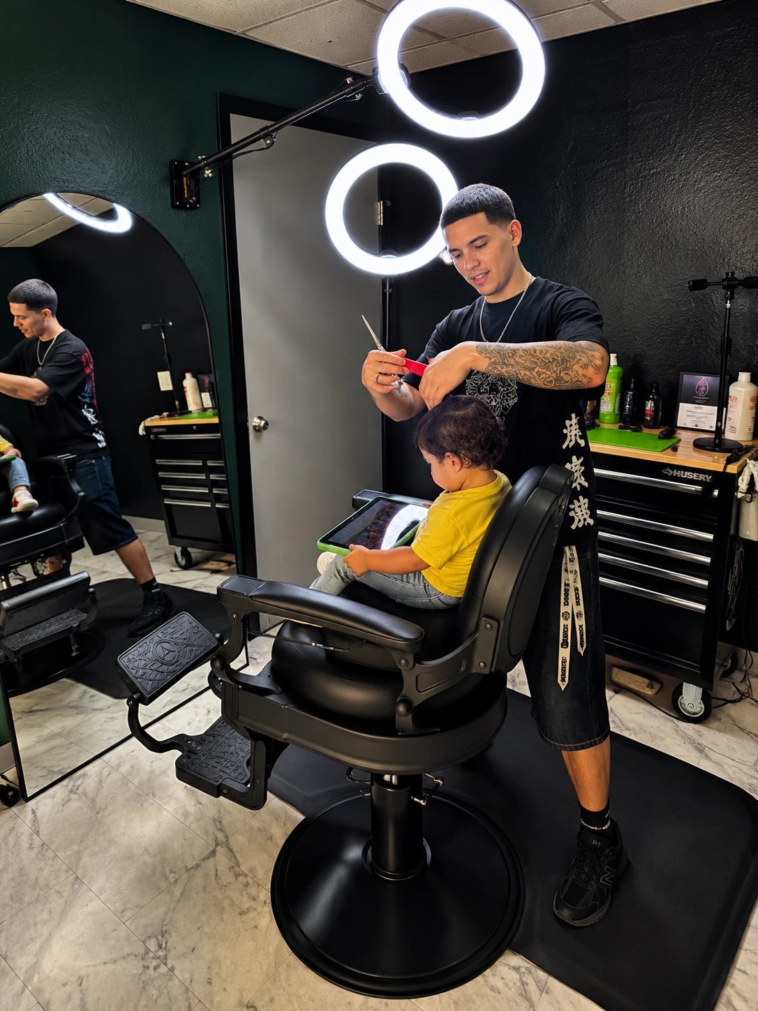 Jeremiah cutting a young client's hair while he sits in the barber chair